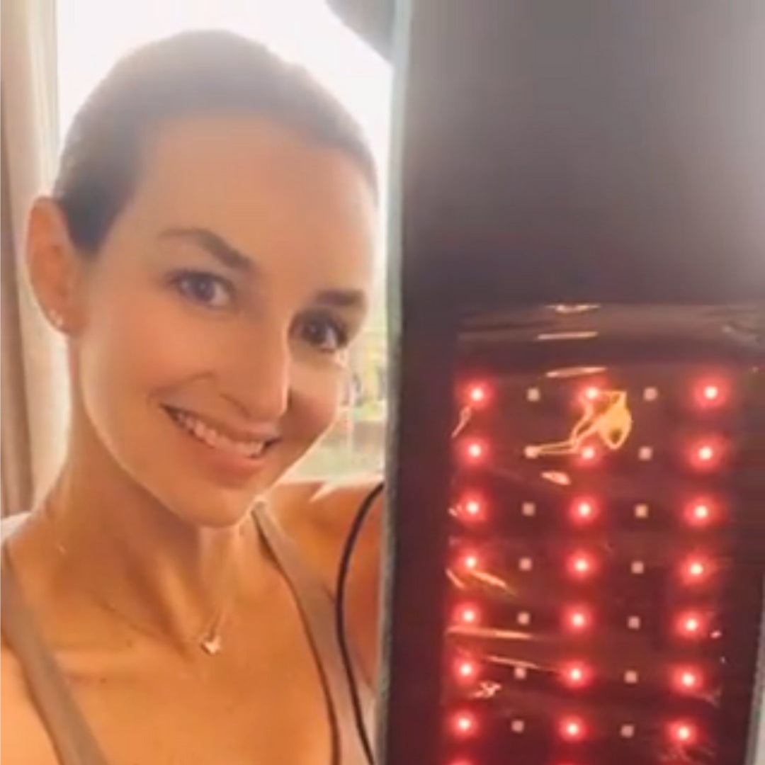 Nő kézben tartott vörös LED-es fényterápiás szalaggal; zsírbontás, bőrfeszesítés, narancsbőr csökkentésének támogatása.